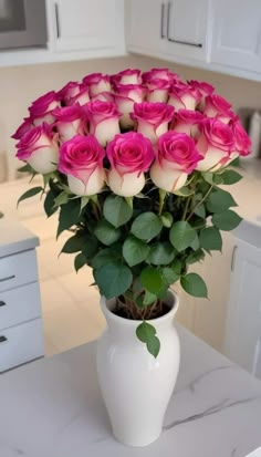 a white vase filled with pink roses on top of a table