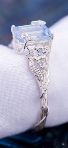 a fancy ring with an aqua blue topazte surrounded by filigrees