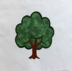 a green tree embroidered onto a white piece of cloth