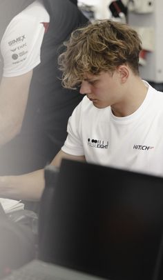 a young man sitting in front of a laptop computer