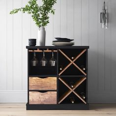 a black cabinet with wine bottles and glasses on it next to a potted plant