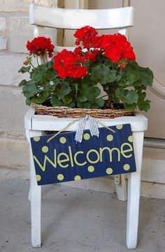 a welcome sign sitting on top of a white chair with red flowers growing out of it