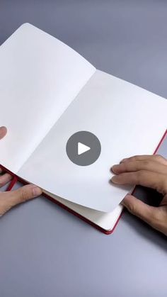 two hands holding an open book on top of a gray surface with the video title