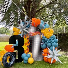 an outdoor birthday party with balloons and decorations on the grass, including a large letter b