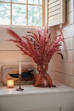 a vase filled with pink flowers next to a lit candle