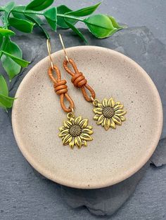 Crafted from knotted tan leather, these boho golden sunflower earrings capture the essence of summer with their lightweight, breezy design. Measuring 2.5" in length, they dangle playfully, adding a whimsical touch to any outfit. Embrace the sunny vibes and cheerful elegance they bring to your look! ♥ All orders come beautifully hand-packaged with care, making it the perfect gift for yourself or someone special. ♥ Each piece is handmade with love in my home studio in Rockaway, NJ. How To Make Sunflower, Boho Leather Jewelry, Golden Sunflower, Gold Flower Earrings, Schmuck Gold, Sunny Vibes, Sunflower Jewelry, Sunflower Earrings, Summer Earrings