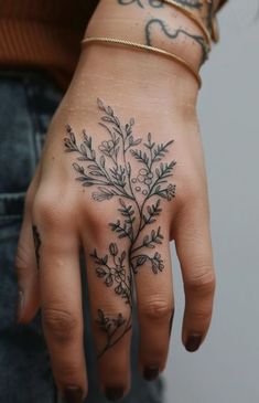 a woman's hand with tattoos on it and flowers tattooed on the palm area