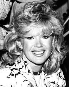 a black and white photo of a woman with blonde hair smiling at the camera,