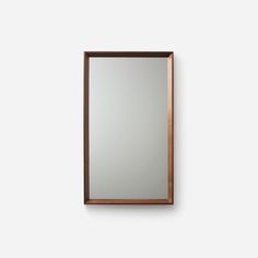 a mirror mounted to the side of a wall with a wooden frame and metal trim