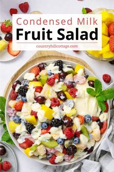 a bowl filled with fruit salad on top of a white table next to other fruits