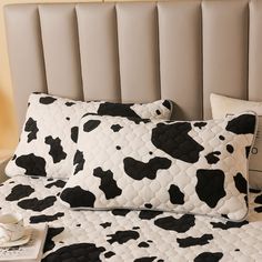 black and white cow print pillow cases on a bed with two pillows next to each other