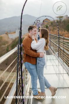 a man and woman kissing on a bridge