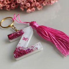 two pink and white acrylic letters with tassels