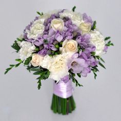 a purple and white bridal bouquet with greenery on the bottom is shown in front of a gray background