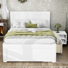 a white bed sitting in a bedroom on top of a wooden floor next to a fire place