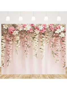 pink and white flowers are hanging from the ceiling in front of a wall with lights