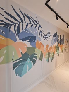 the wall is painted with colorful leaves on it and has white marble flooring in front of it