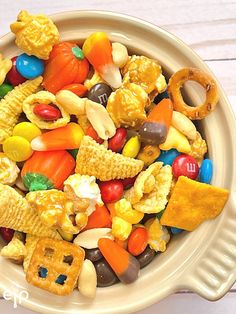 a bowl filled with candy corn, cheetos and pretzel crackers