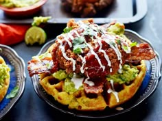 two waffles topped with meat, guacamole and sour cream drizzled on top