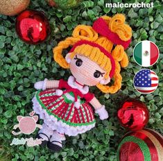 a crocheted doll laying in the grass next to christmas ornaments