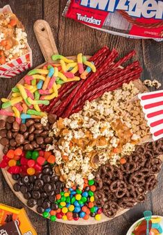 a wooden platter filled with popcorn, candy and candies