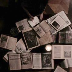 an overhead view of many open books on the floor with one candle lit in front of them