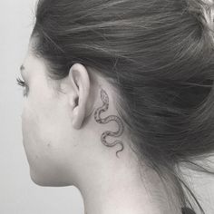 a woman with a snake tattoo on her left side behind her ear, looking to the right