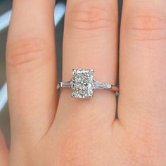 a woman's hand with a diamond ring on top of her finger and the engagement band