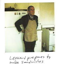 a man wearing an apron standing in front of a refrigerator with his hands on his hips