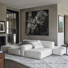 a living room with a large painting on the wall and white furniture in front of it