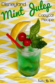 a green drink with cherries and lemon wedges in it on a checkered table cloth