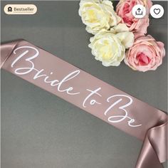 the bride to be sash is next to some pink and white flowers on a table