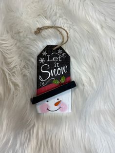 a snowman ornament hanging on a white furnishing with the words let it snow