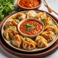 some dumplings are on a plate with sauce and garnishes next to them