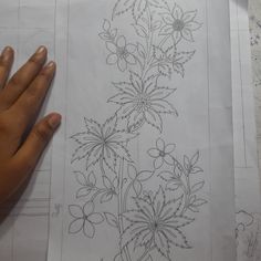 someone is holding their hand on top of some paper that has flowers drawn on it