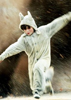 a young boy dressed in an animal costume skates through the snow with his arms outstretched