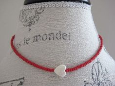 a red string necklace with a white heart on it