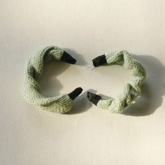 two pieces of knitted fabric are arranged in the shape of a heart on a white surface