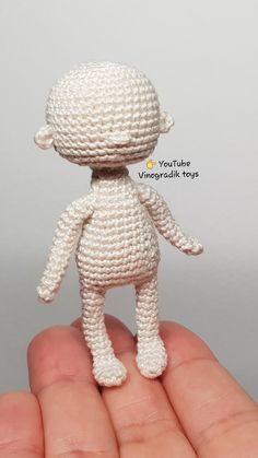 a small white crocheted stuffed animal sitting on top of a person's hand