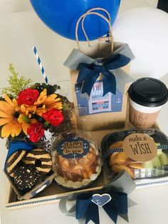 a box filled with lots of food and drinks on top of a table next to balloons