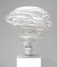 a white sculpture sitting on top of a wooden block with spirals in it's center