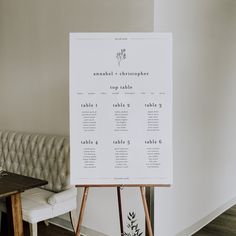 a seating chart is displayed on an easel in front of a white couch and table