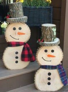 two snowmen made out of wood sitting on the steps next to a planter