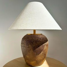 a table lamp sitting on top of a wooden table next to a white light shade