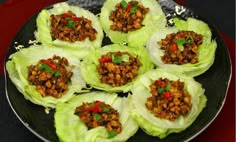 lettuce wraps filled with meat and vegetables on top of a black platter