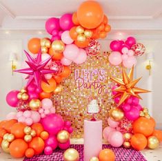 a table topped with balloons and stars next to a wall covered in confetti