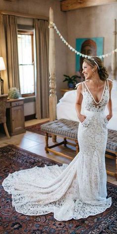 a woman in a wedding dress is standing near a bed