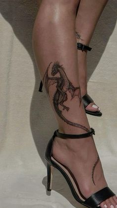 a woman's legs with tattoos on them and her shoes in the shape of a dragon