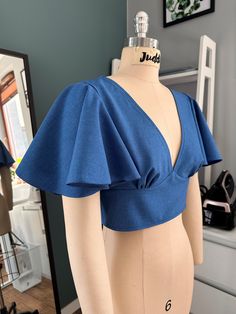 a mannequin wearing a blue top with ruffles on it's shoulders