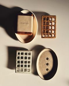 three ceramic objects on a white surface with shadows from the top one has a stamp, and the other two are empty